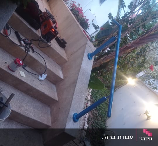 מעקה כחול מותקן על מדרגות בטון